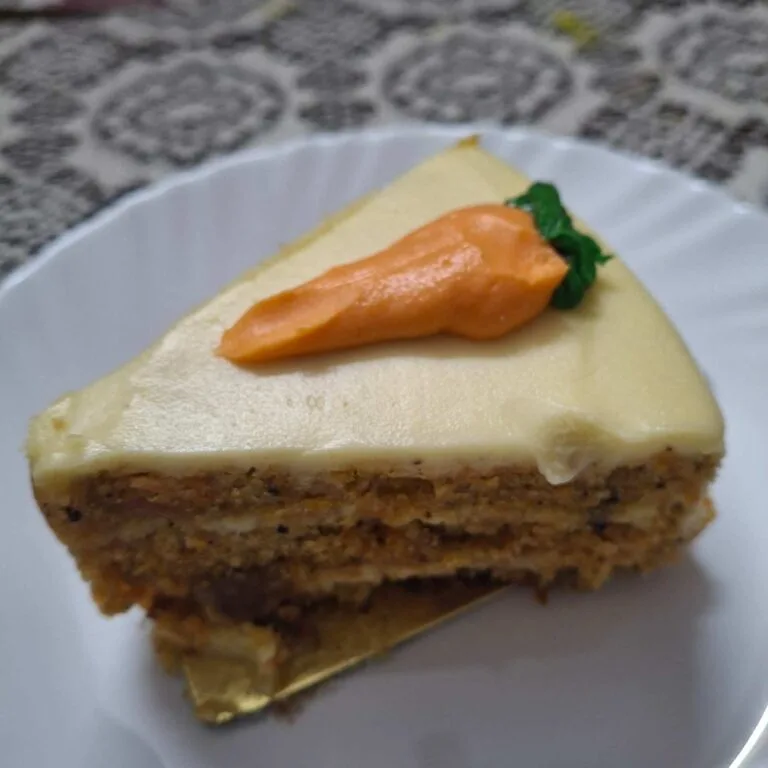 Creamy carrot cake cheesecake slice with cream cheese frosting and pecans